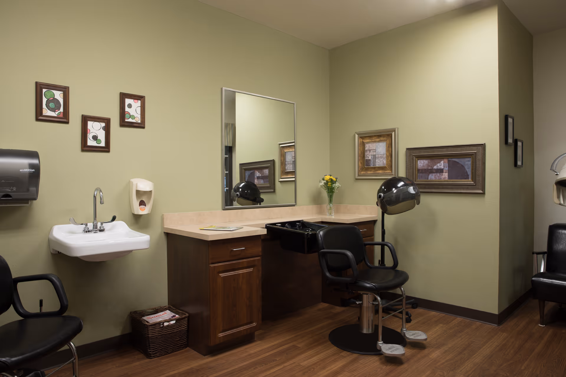 Interior of a senior living facility hair salon with a sink, mirror, and styling chair.