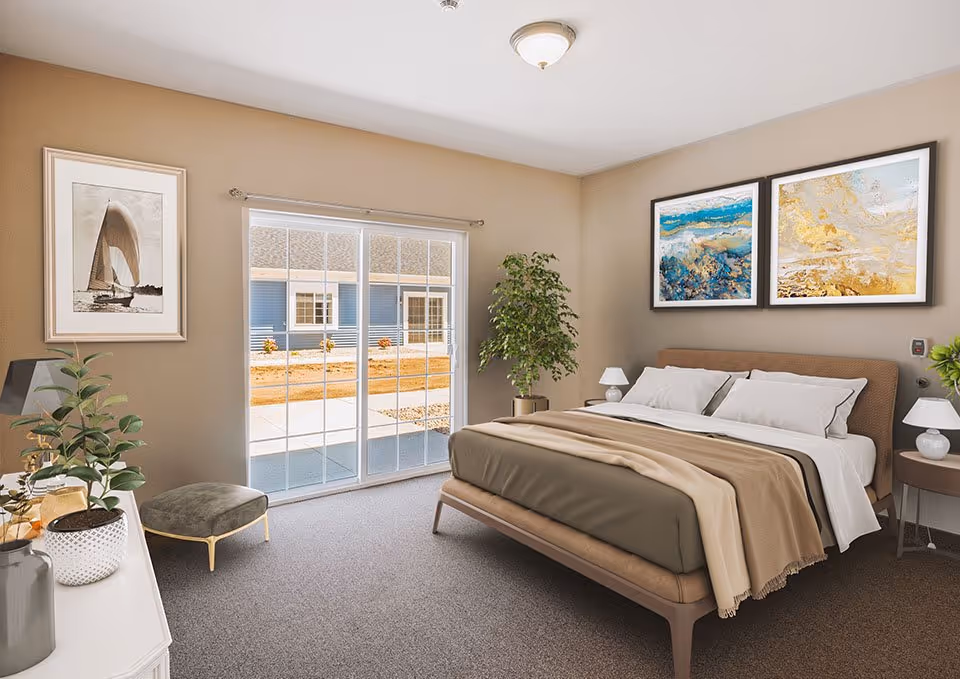 Sunlit furnished bedroom with a bed, nightstands, artwork, plants, and sliding glass doors leading outside.