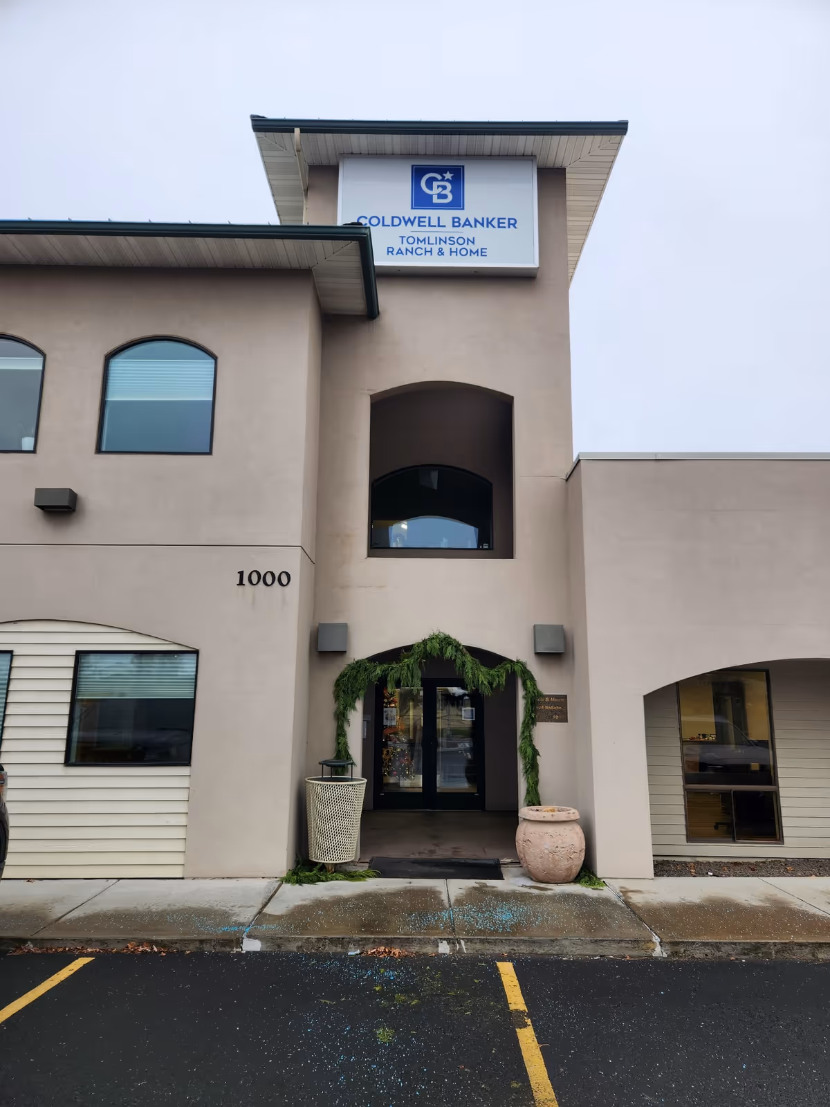 Beige building entrance with vines, a planter, and a Coldwell Banker sign.