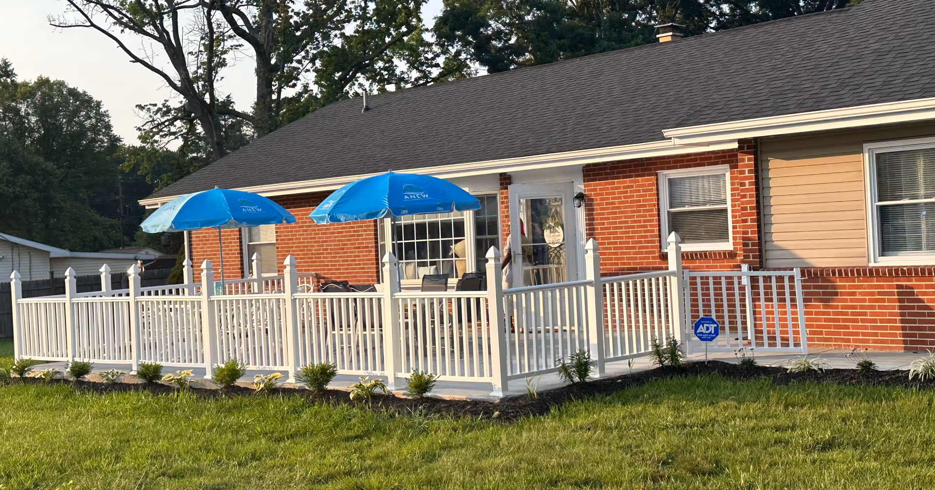 Brick single-story building with a white deck railing and blue patio umbrellas.