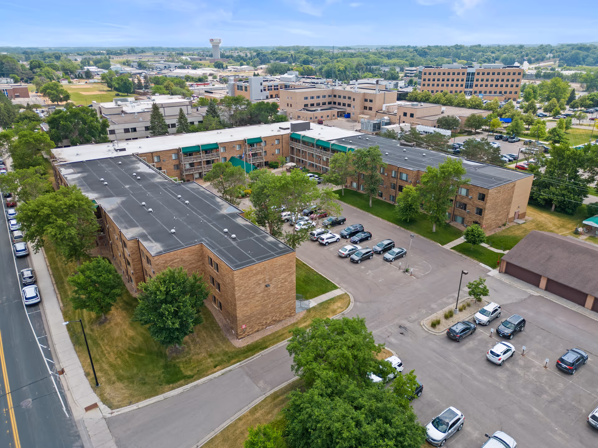 Aerial view of a senior living campus with brick buildings, parking lot, and trees.