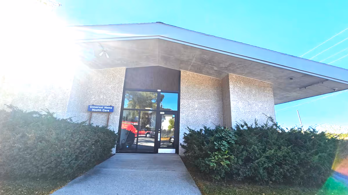 Exterior view of Universal Home Health Care entrance with glass doors and surrounding bushes.