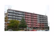 Exterior view of a multi-story senior living building with balconies and parked cars.