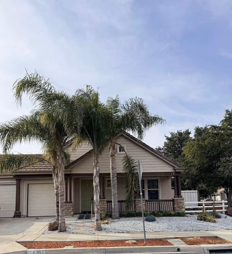 Single-story facility building with a front porch, palm trees, and gravel landscaping.