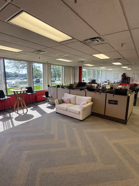 Bright interior of a senior living facility featuring a beige sofa, small tables, and office desks.