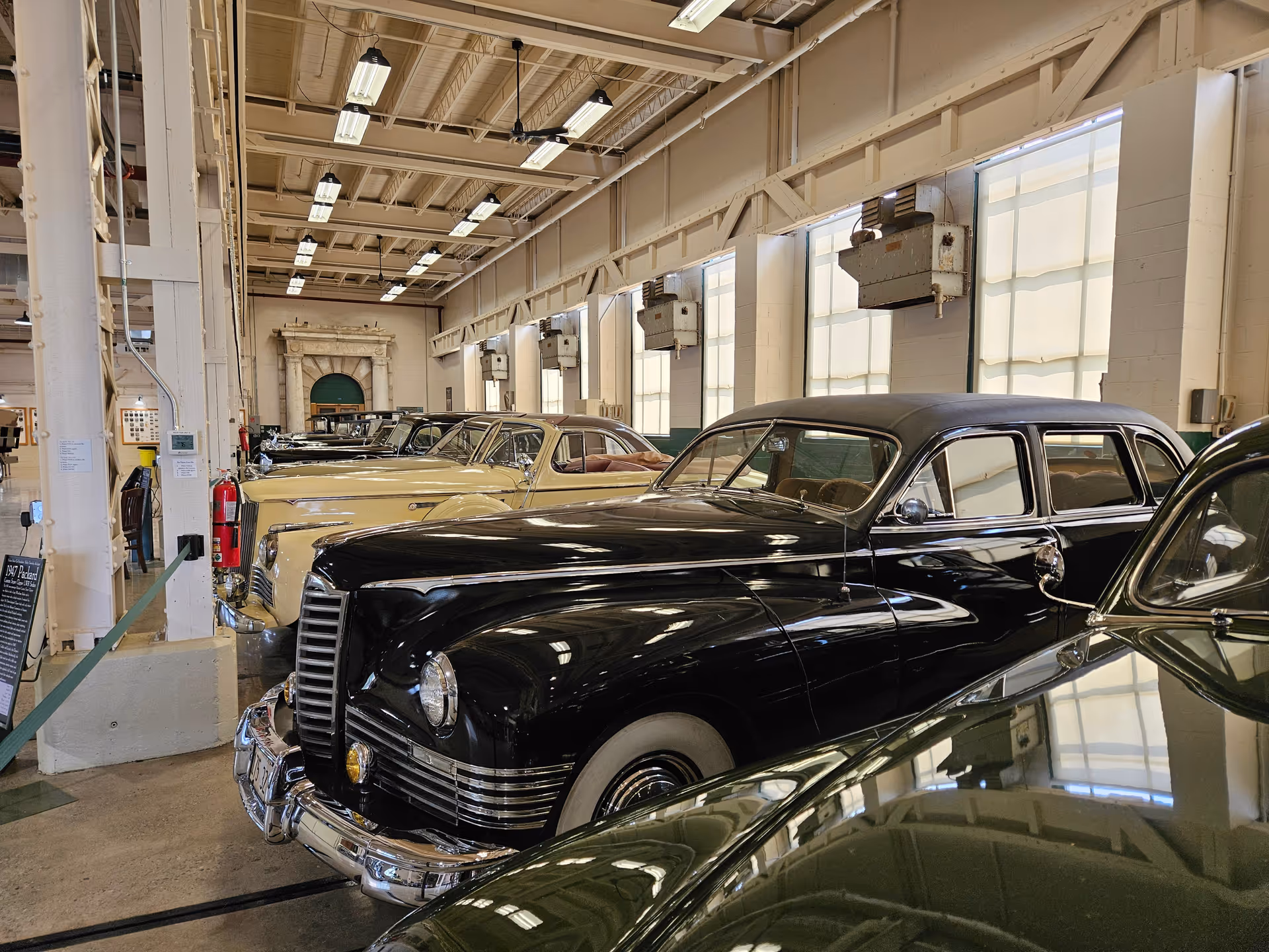 Indoor showroom with a row of vintage black and cream cars.