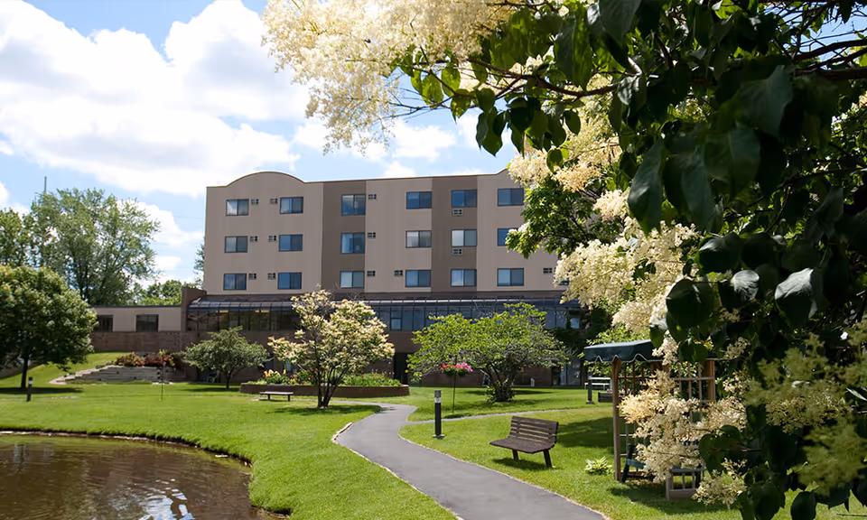 Chandler Place building with green lawn, trees, benches, and a winding path.