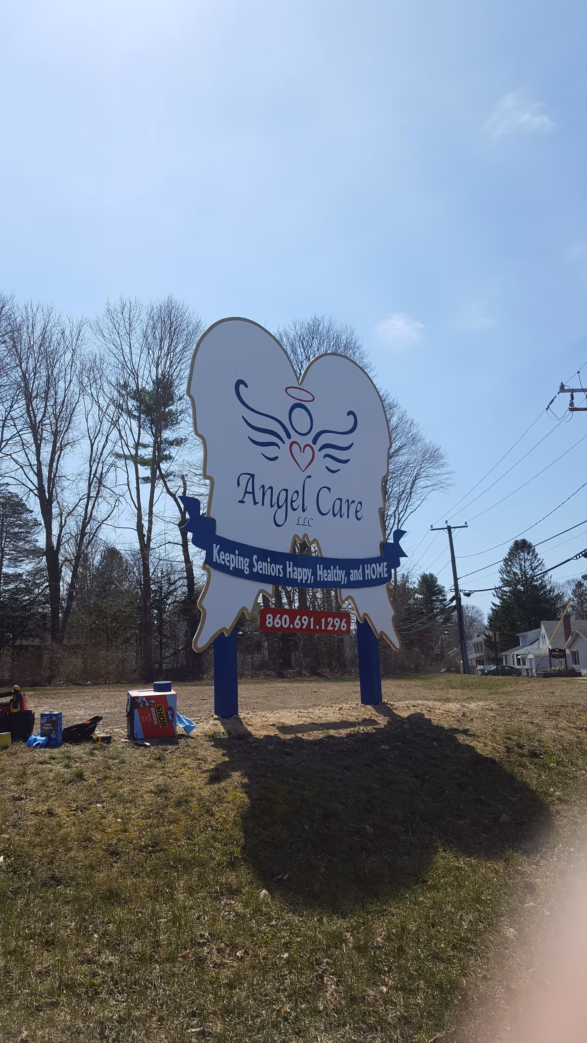 Large Angel Care LLC sign on a grassy roadside with trees behind.