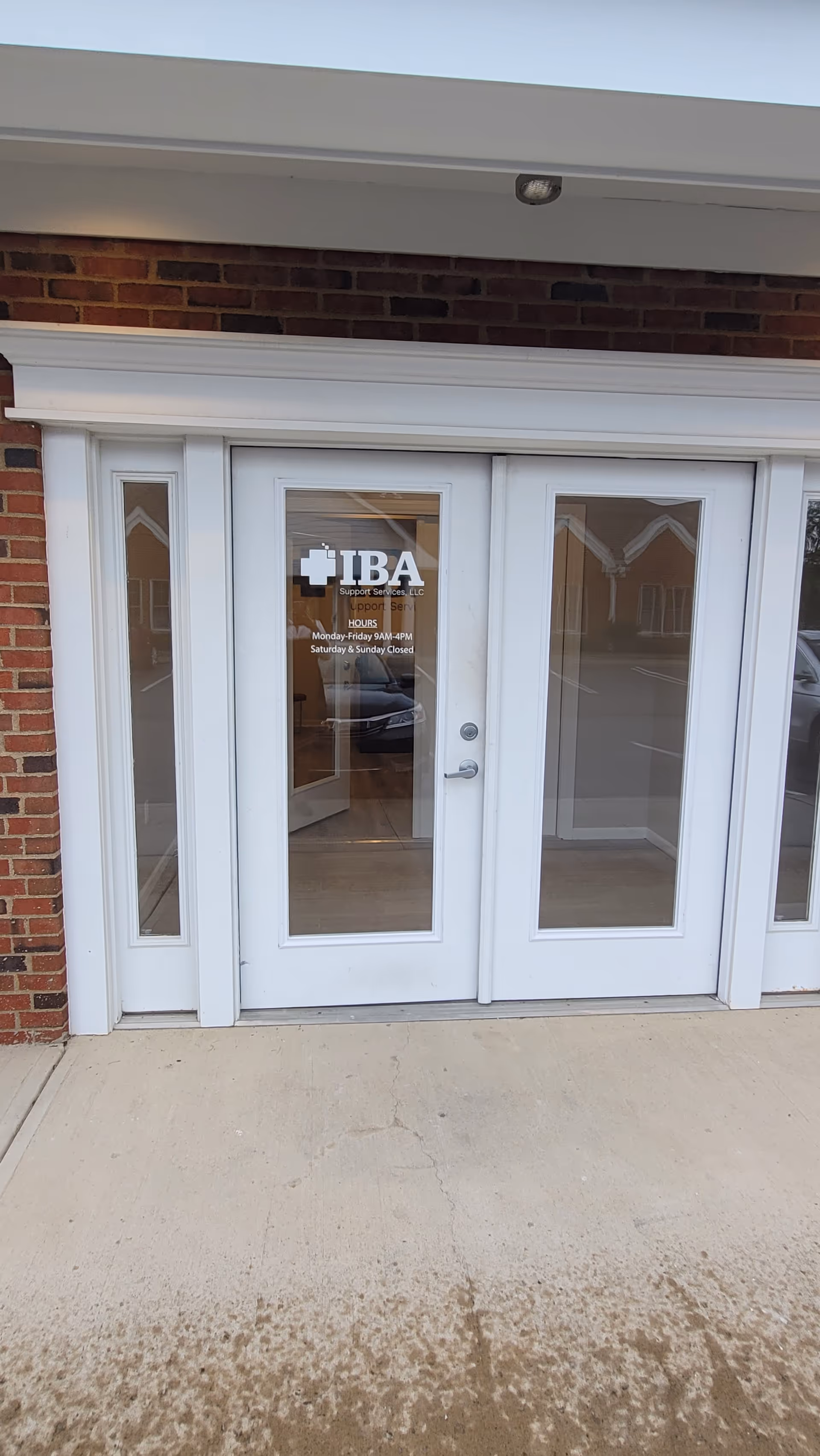 White exterior doors with glass panels and an IBA Support Services logo on entrance.