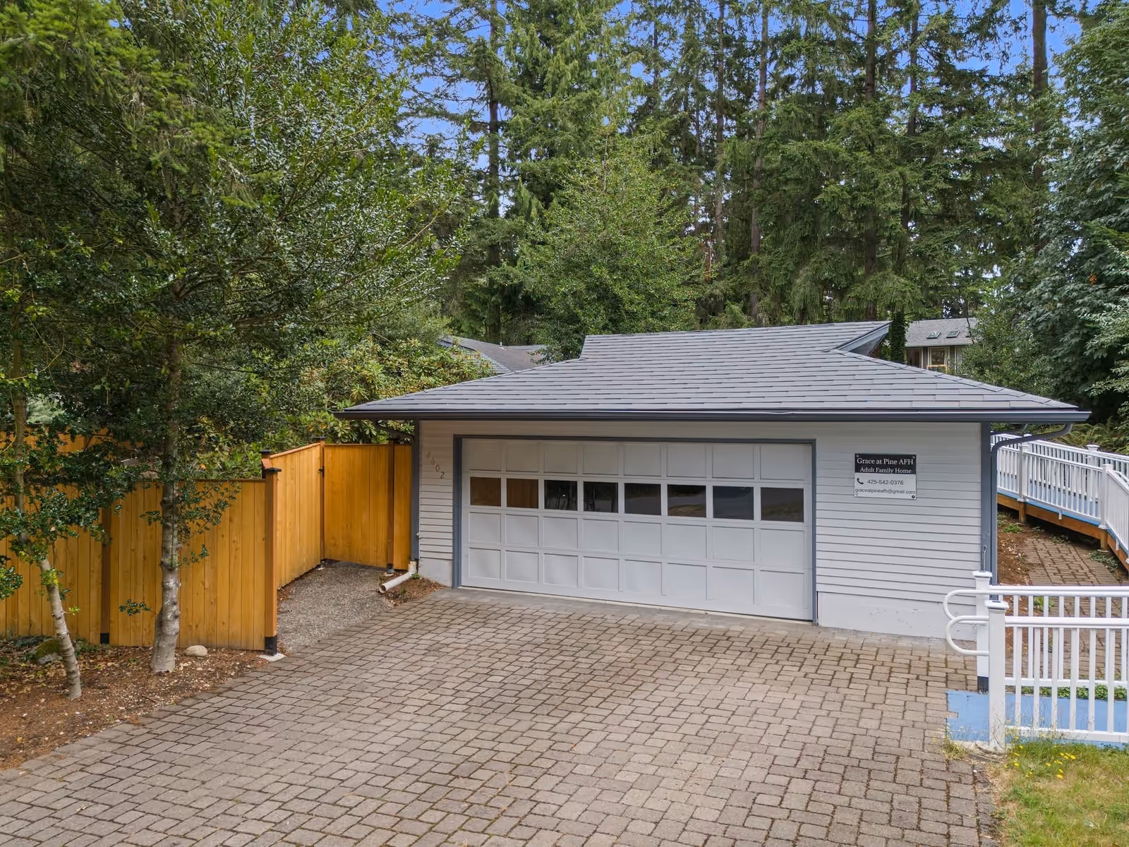 Front view of Grace at Pine AFH building with a large garage door and surrounding trees.