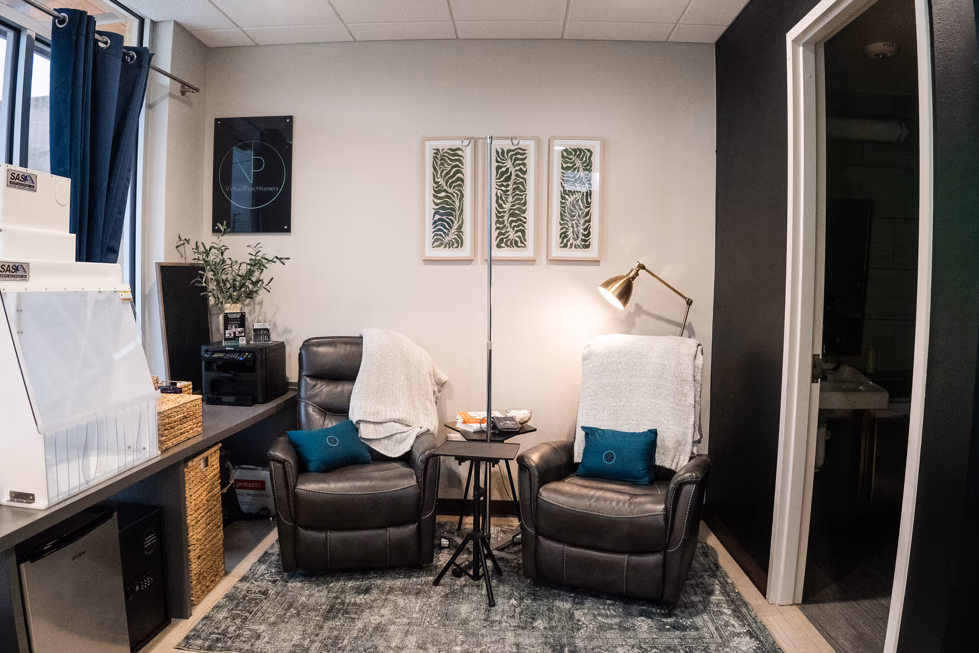 Two black leather recliners with a side table and lamp in a cozy lounge.