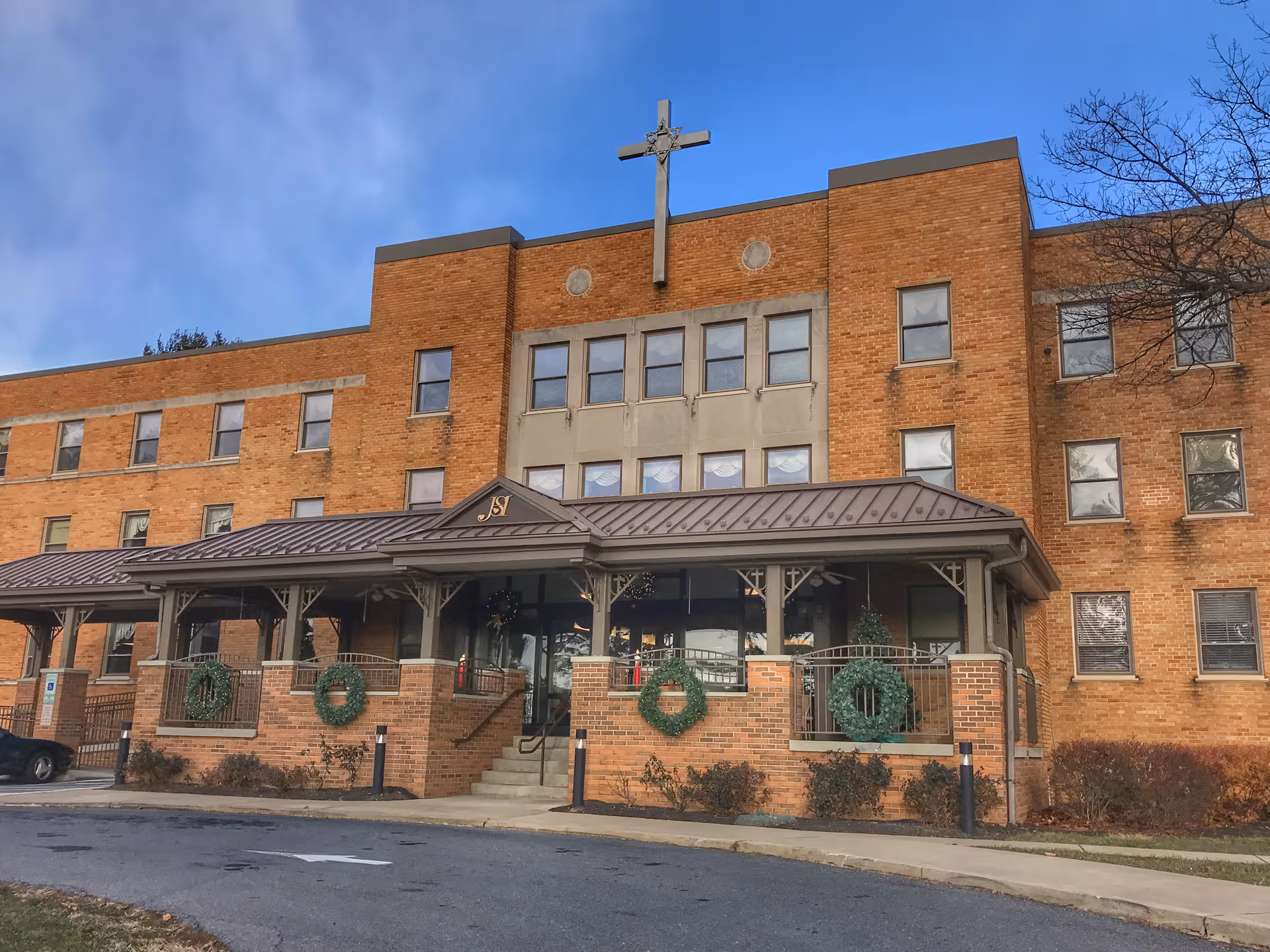 Exterior view of a brick senior living building with a covered entrance and wreaths.