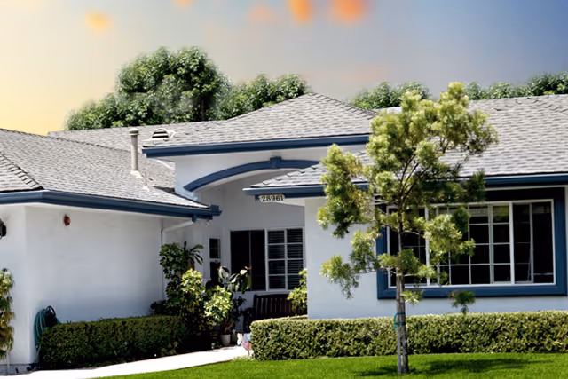 White single-story senior living building with blue trim, front entrance, and manicured landscaping.