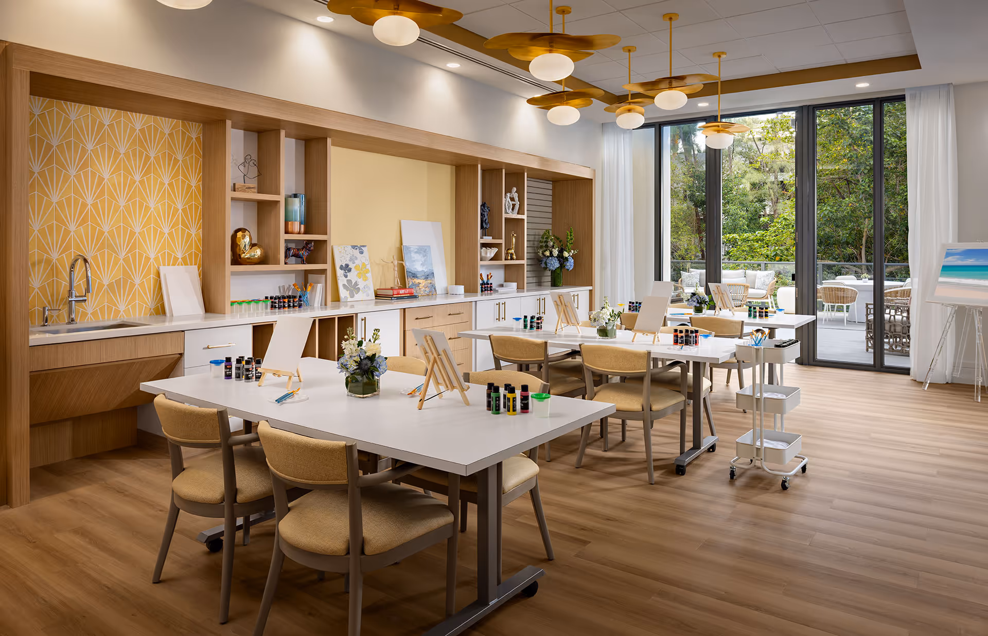 Bright craft studio with tables, easels, shelves, and large windows in Belmont Village Senior Living Aventura