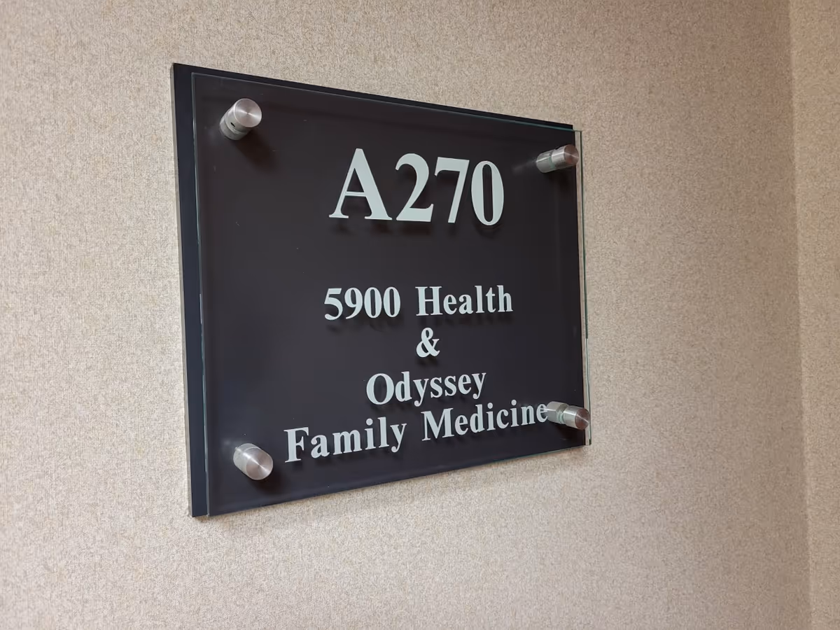 Wall-mounted black plaque on beige wall reads A270 and 5900 Health & Odyssey Family Medicine.