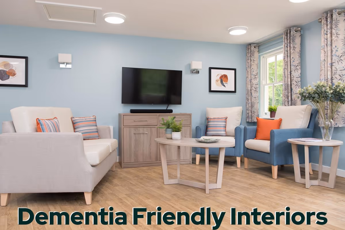 A bright dementia-friendly living room with blue walls, seating, coffee table, and TV.