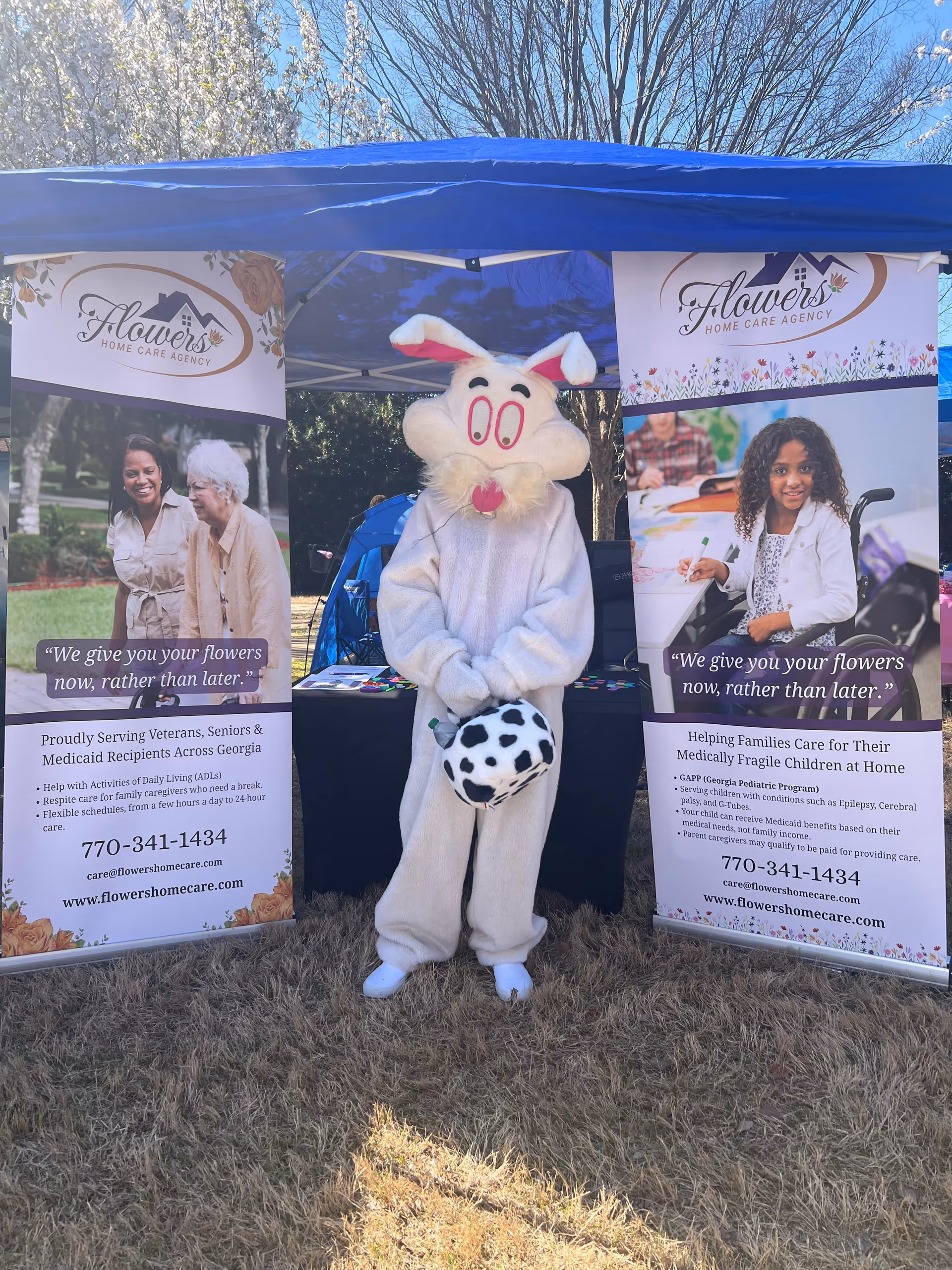 Outdoor booth for Flowers Home Care with a bunny mascot between banners.