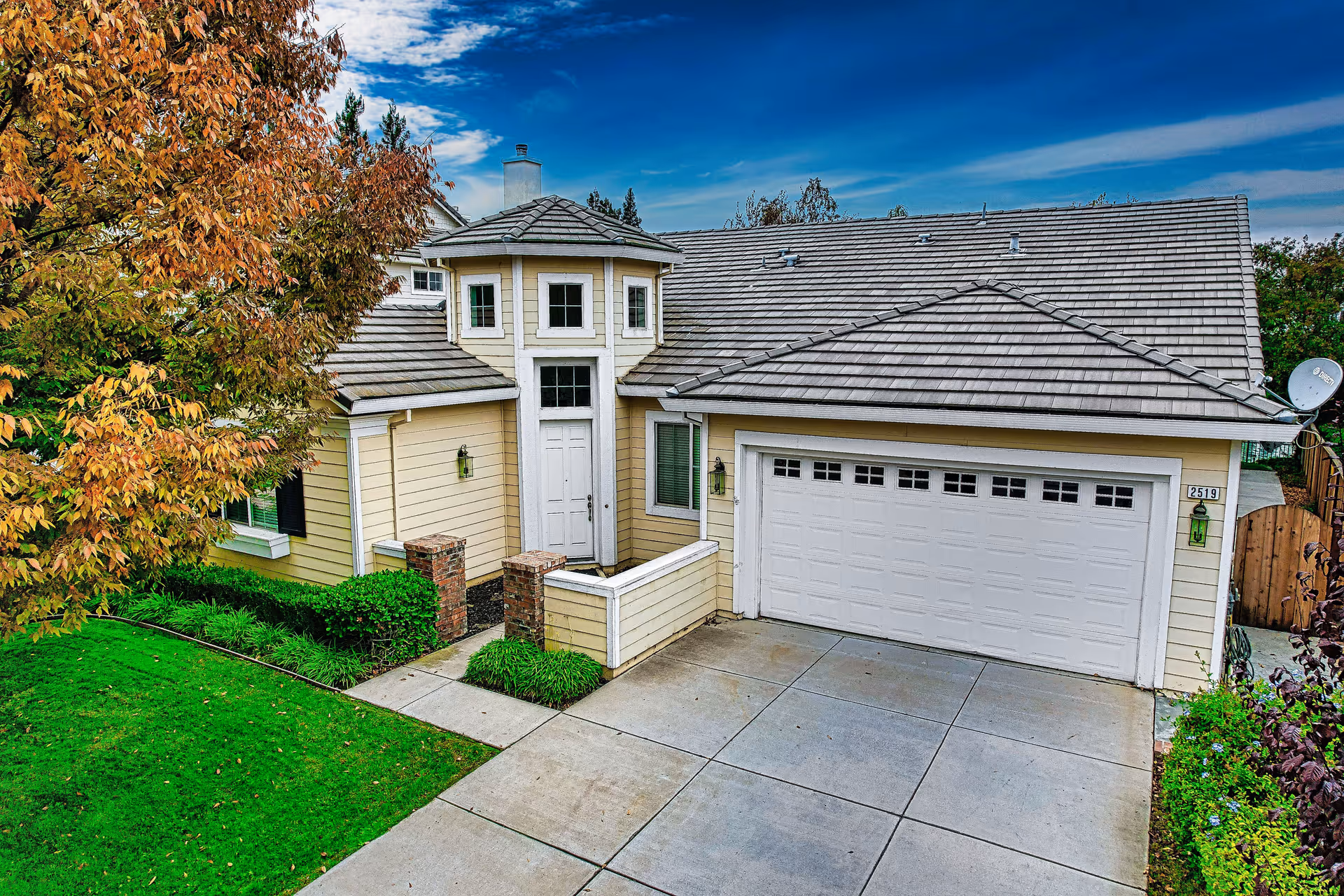 Exterior view of a beige home with a two-car garage and well-kept yard.
