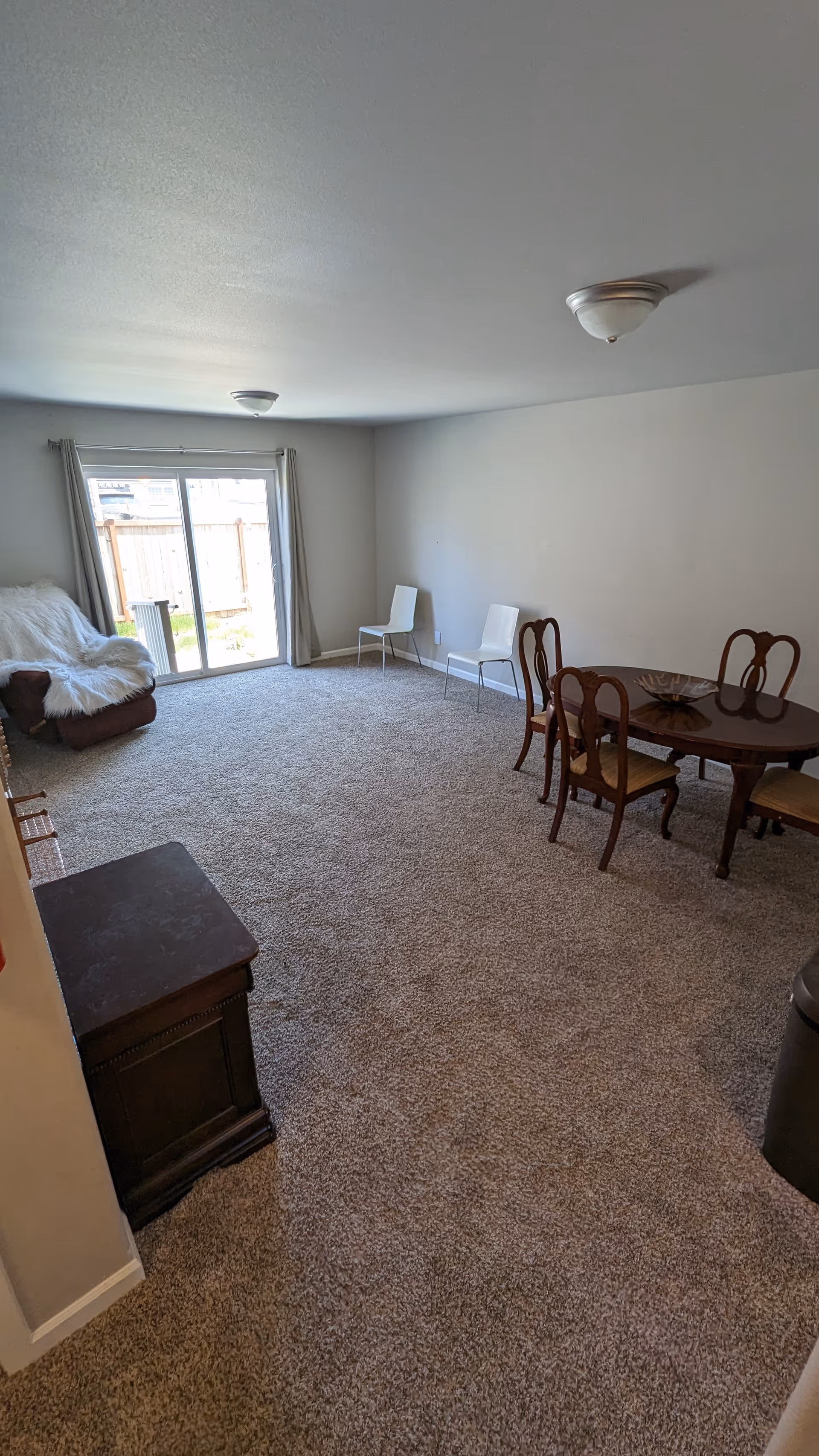 Spacious living area featuring a dining table with chairs beside a sliding glass door.