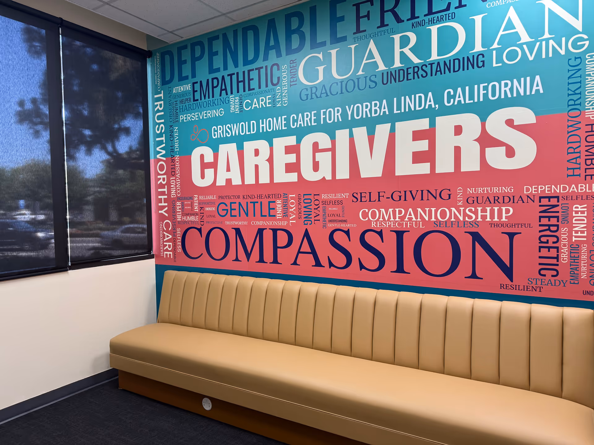 Interior waiting area with a long beige bench against a colorful wall mural.