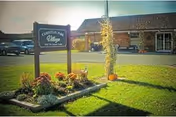 Exterior view of Christian Park Village with a sign, flower bed, and green lawn