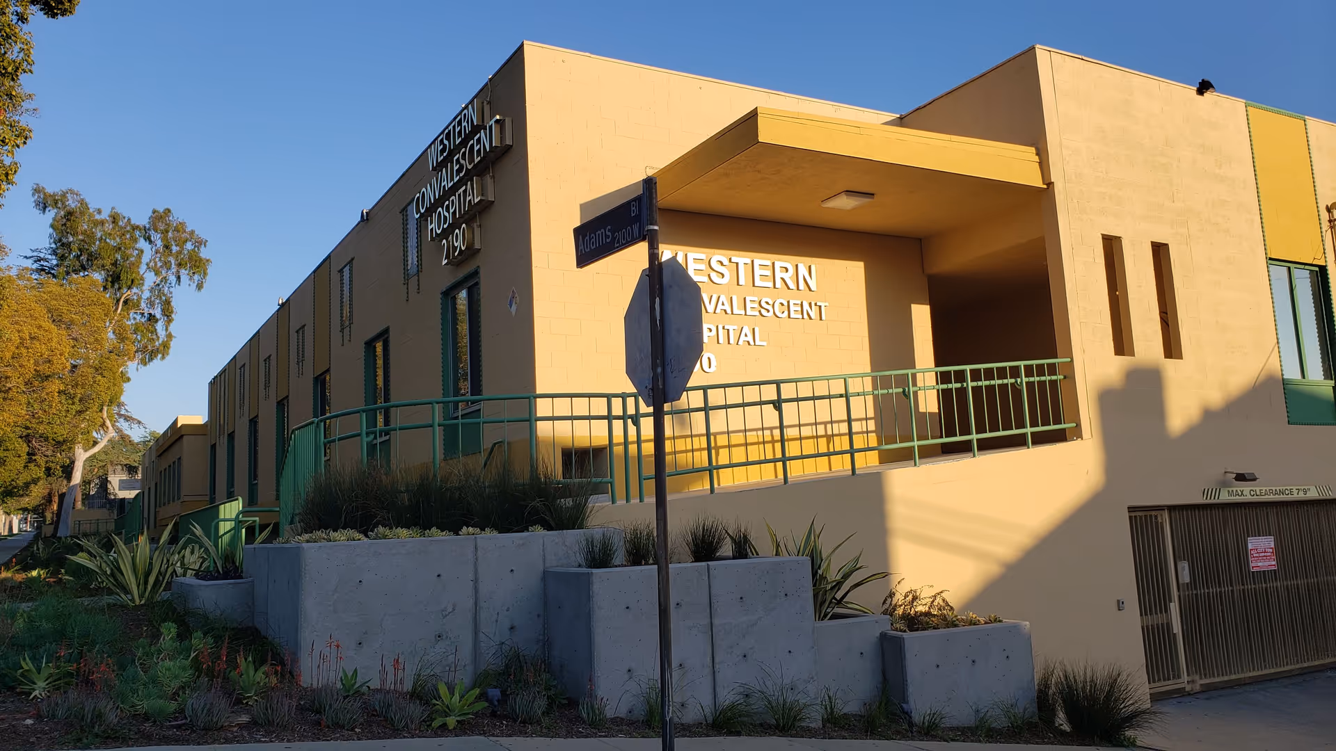 Exterior view of a yellow hospital building with a ramp and planters.