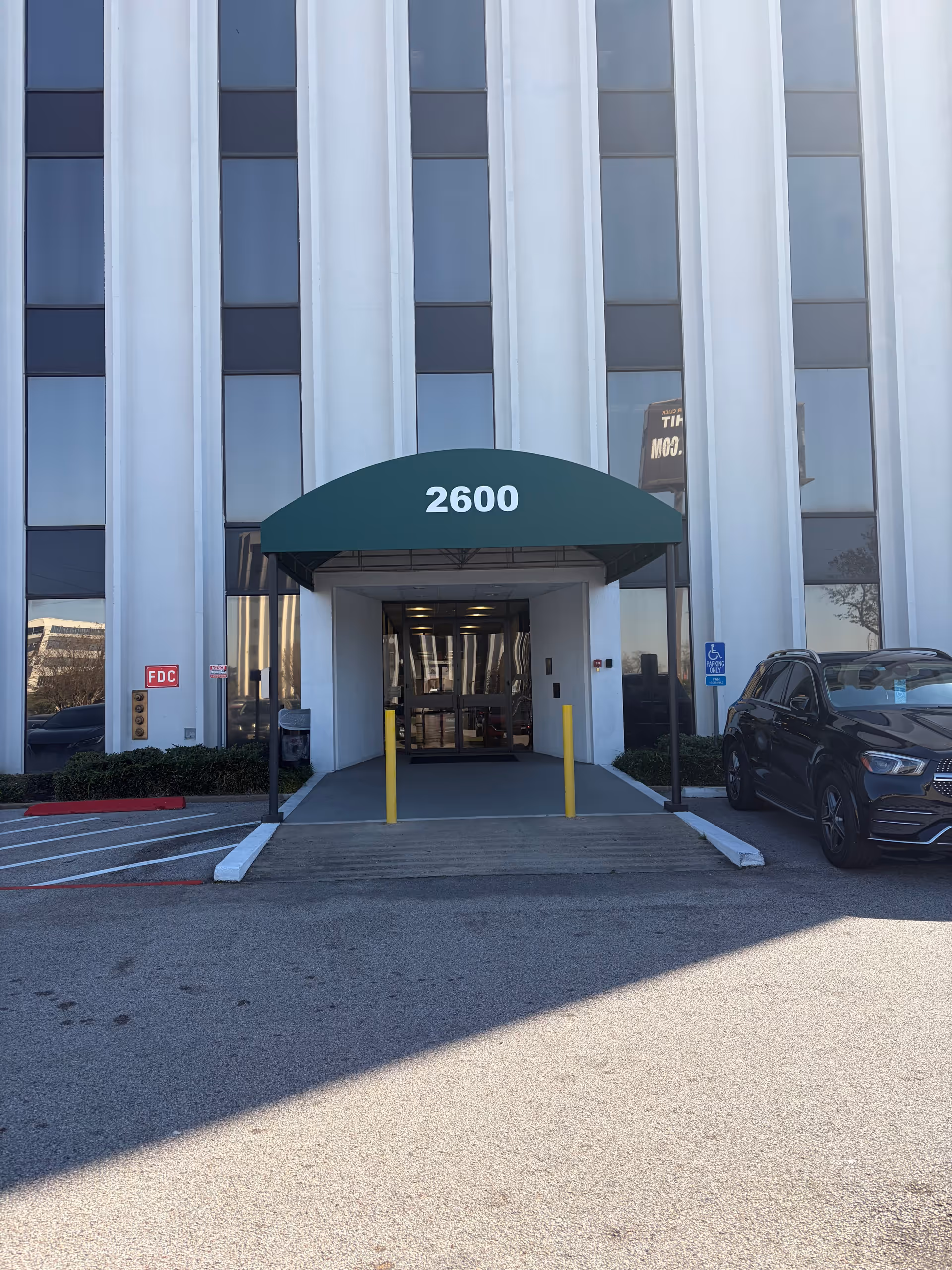 Tall glass-front building with a curved green canopy over the entrance and 2600 sign.