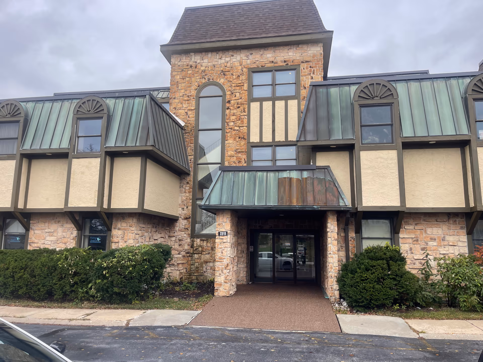 Exterior view of a stone and beige senior living building with glass entrance.