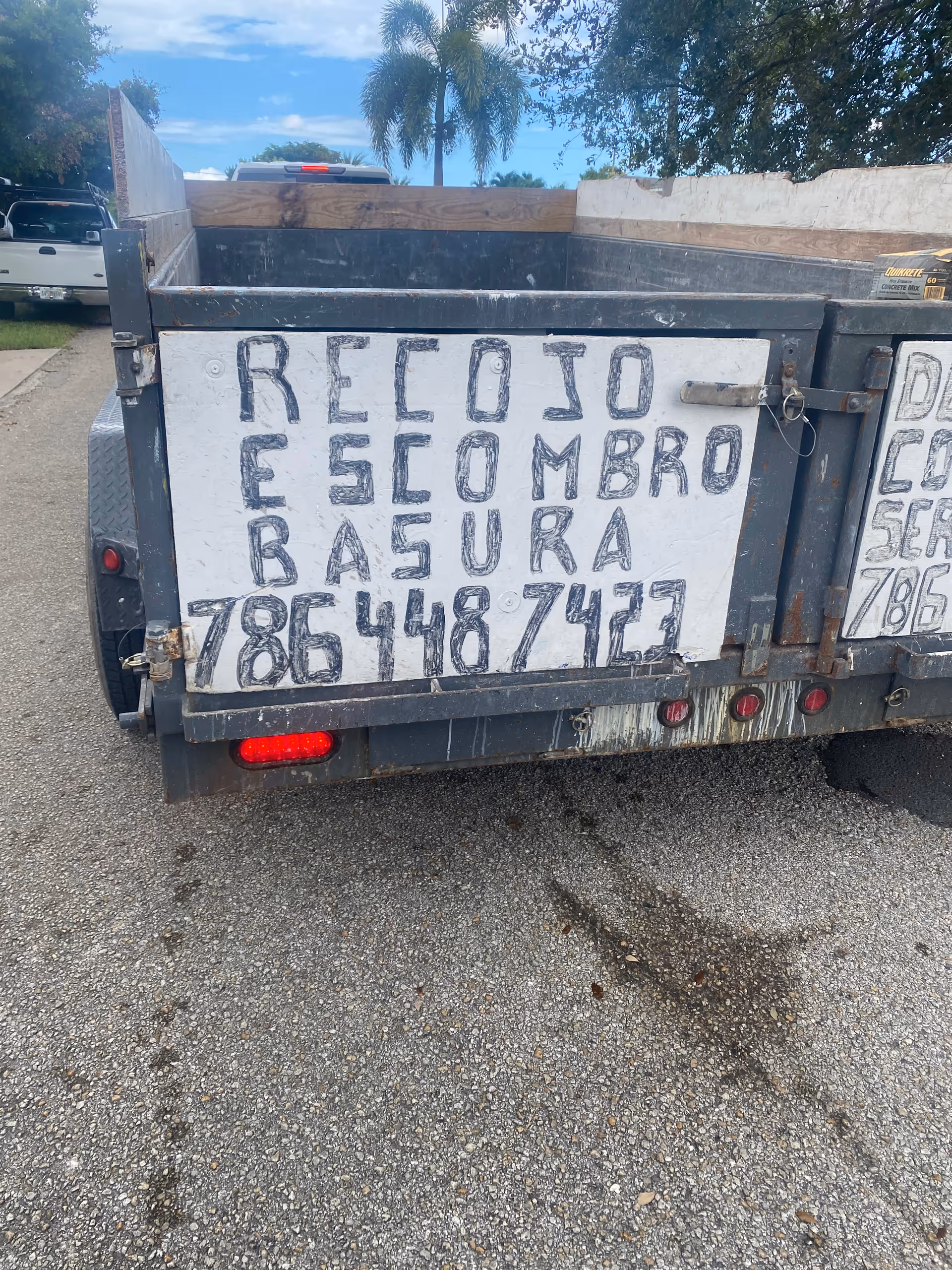 A large metal dumpster with graffiti on a white front panel in a parking lot.