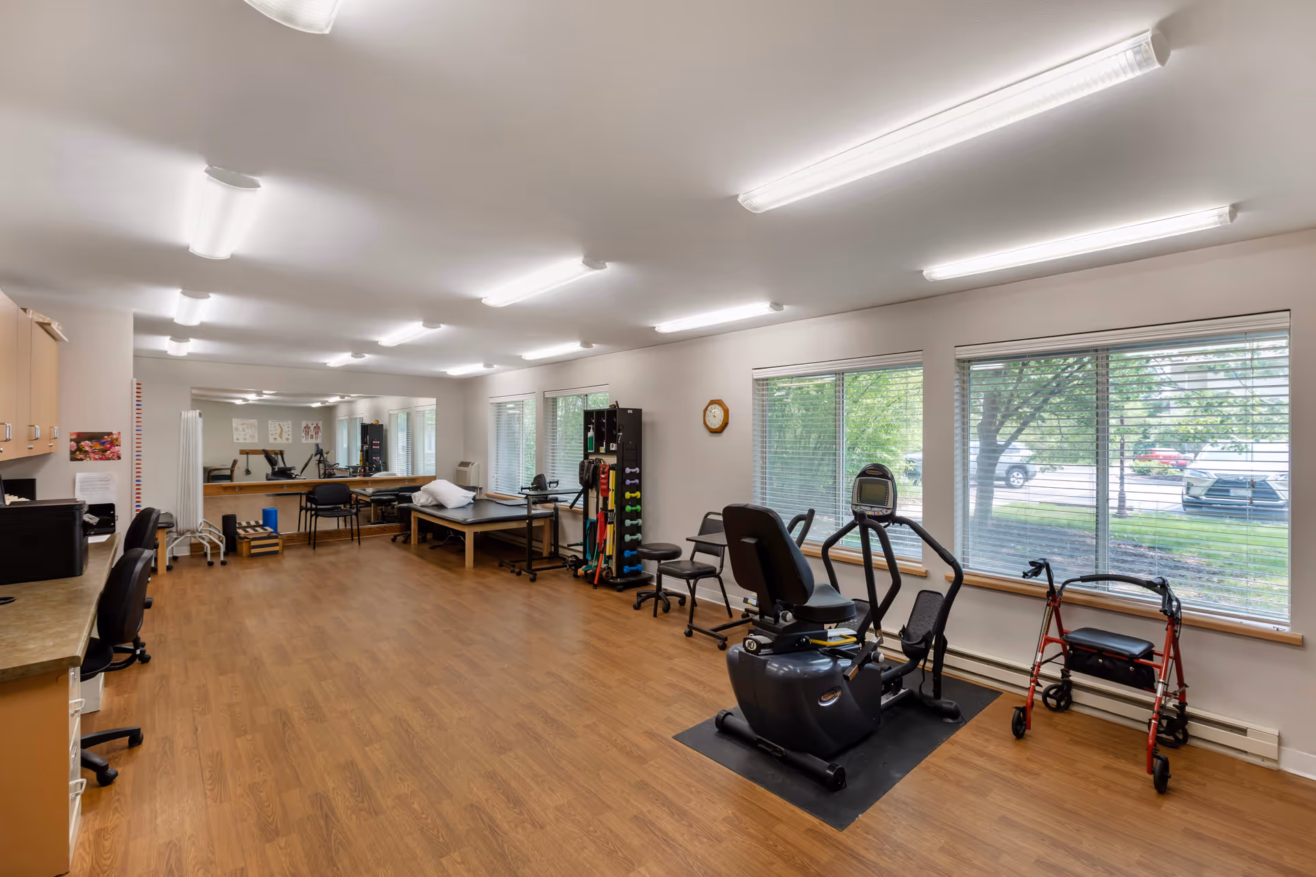 Interior senior living fitness room with cardio equipment and large windows.