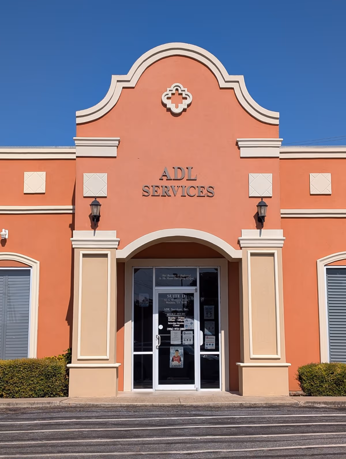 Front view of a peach-colored ADL Services building with arched entry and glass doors