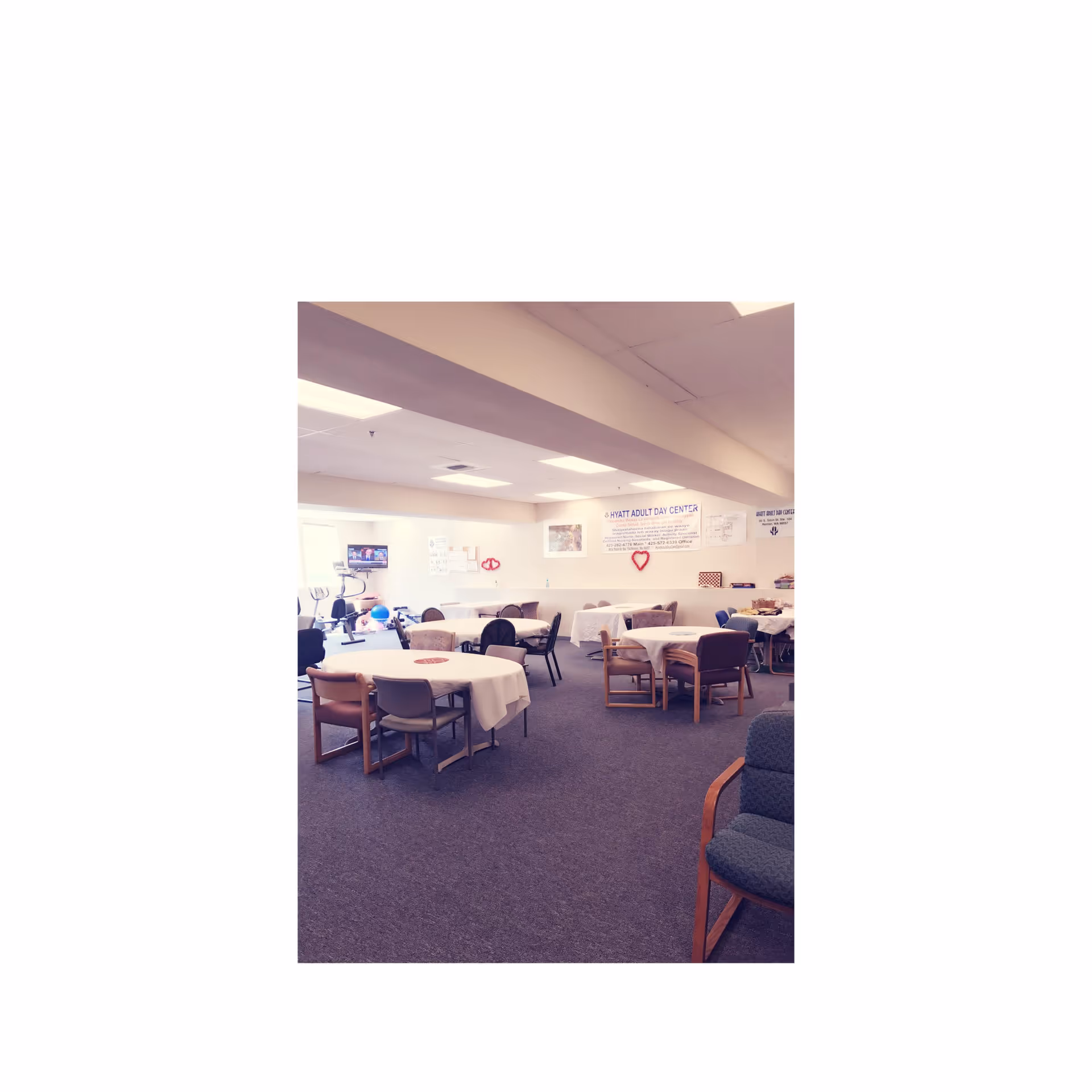 Interior dining room with round tables and chairs in a senior care facility.