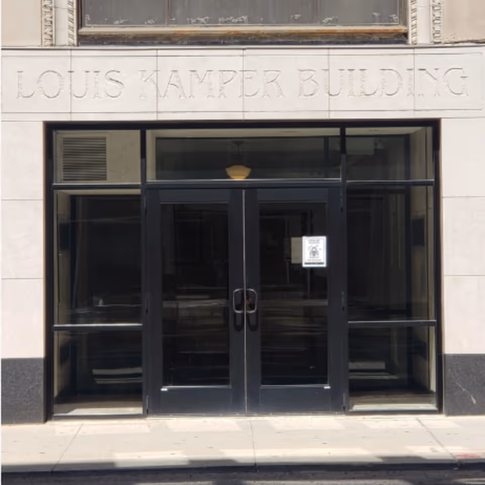 Kamper Stevens Apartments entrance with glass doors and stone facade.
