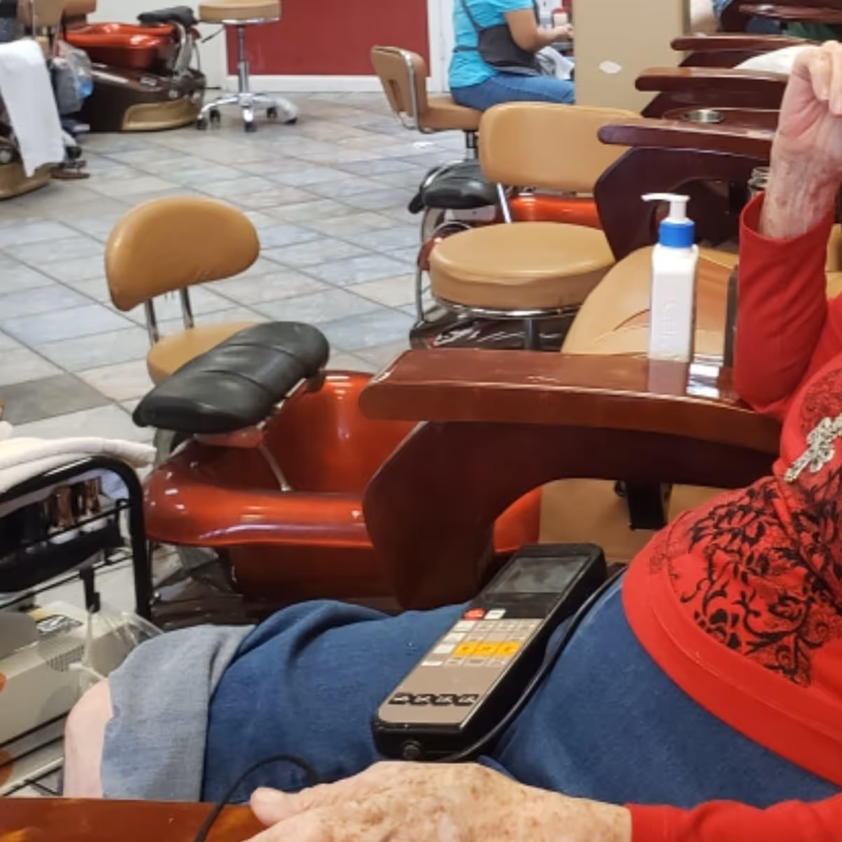 Salon area inside a senior home with red chairs, equipment, and sanitizer on a table.