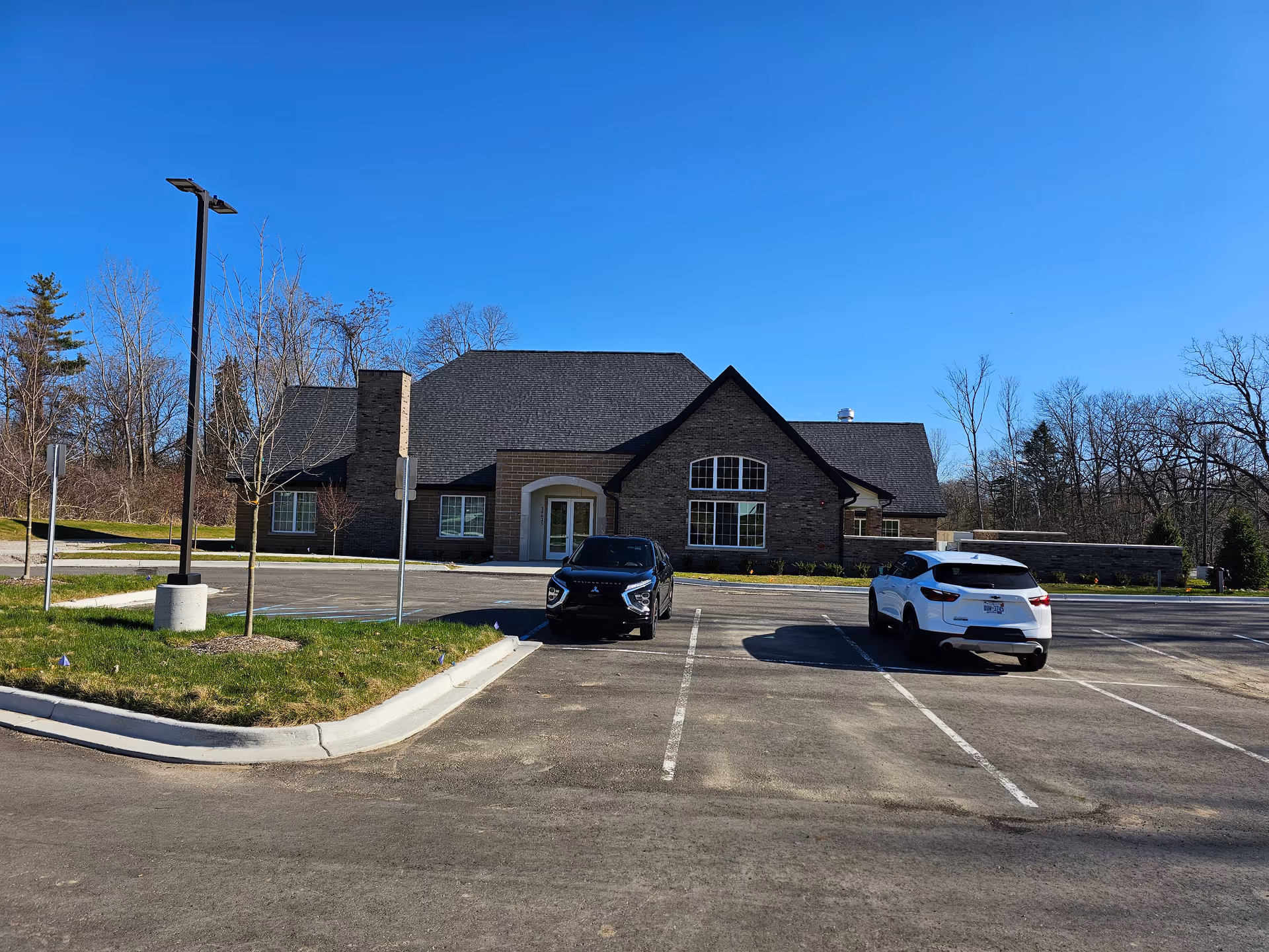 Front view of a brick senior living facility with a parking lot and two cars.