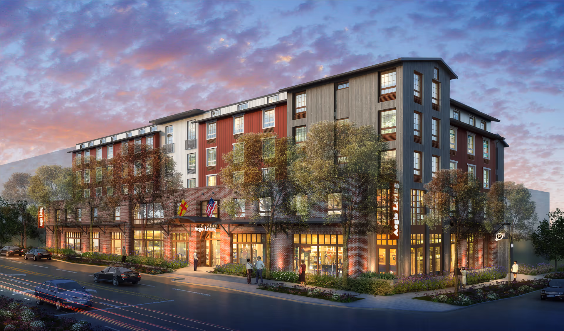 Exterior view of a multi-story senior living facility named Aegis Living Ballard at dusk, with warm interior lights visible through large windows, trees and landscaping around the building, and cars parked along the street in front.