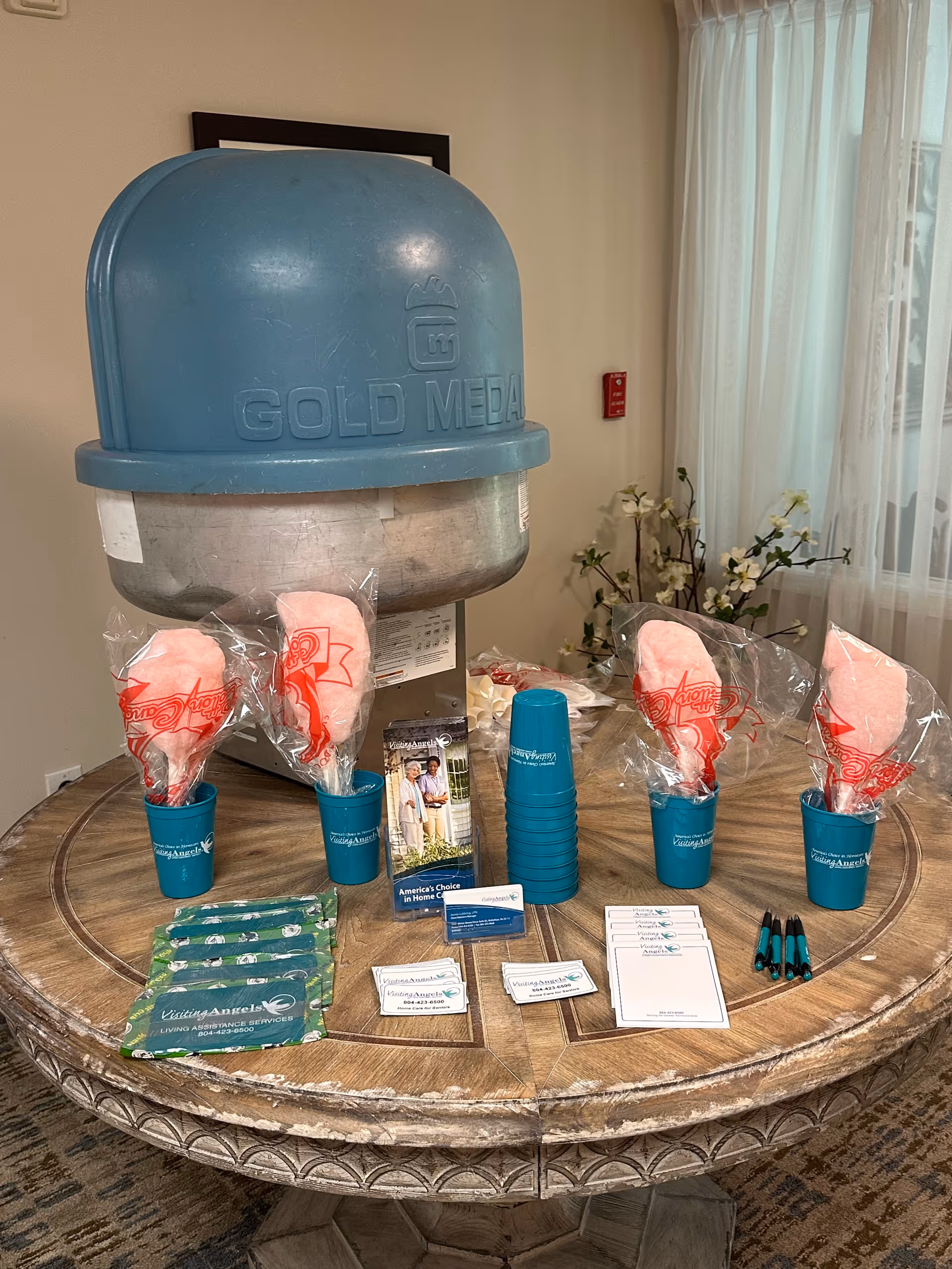 Round wooden table with a large blue dispenser and brochures in a care facility