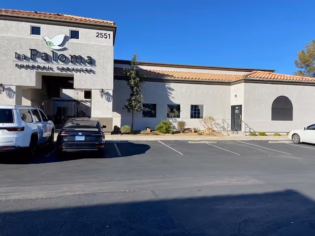 Exterior of La Paloma facility with parked cars and a blue sky.
