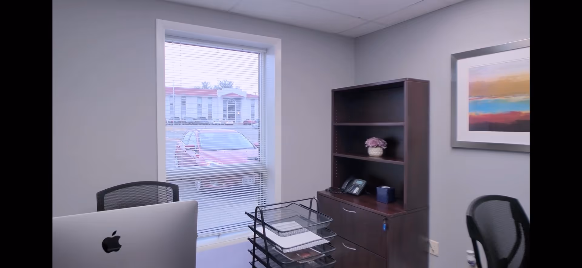 Small office in a senior living facility with computer, cabinet, shelves, and a window.