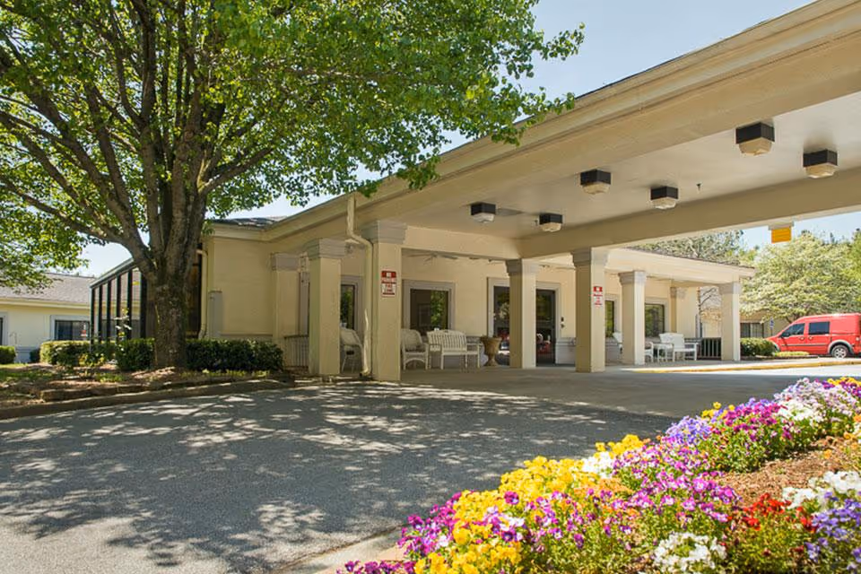 Front exterior of Life Care Center of Gwinnett with a covered entrance and flowers.