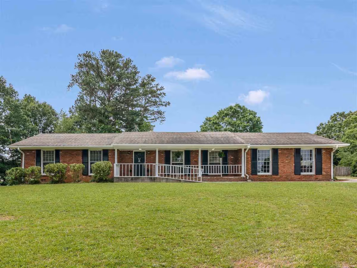 Single-story brick ranch-style building with a covered front porch, wheelchair ramp, and a large grassy lawn.