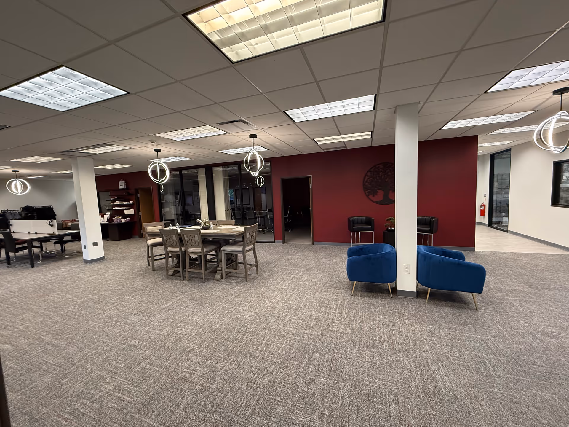 Interior of a senior living common area with a dining table, blue chairs, and maroon wall.