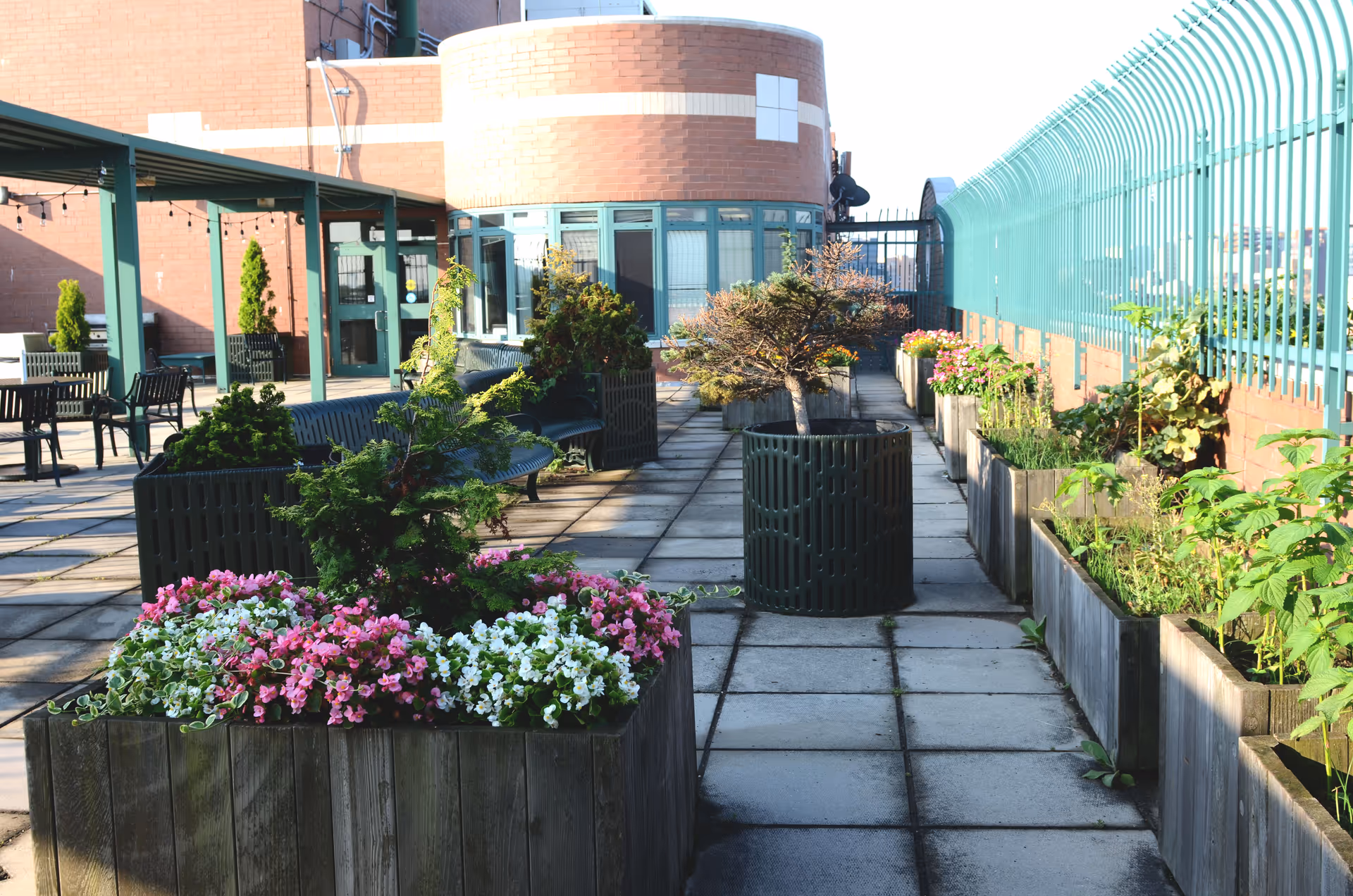 Outdoor courtyard at Union Plaza Care Center with potted plants, benches, and a glass-walled railing.