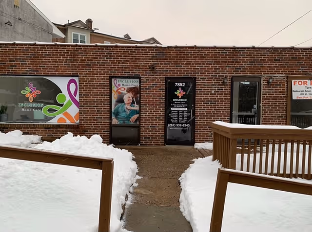 Brick exterior of Inclusion Home Care building with two doors and snowy walkway.