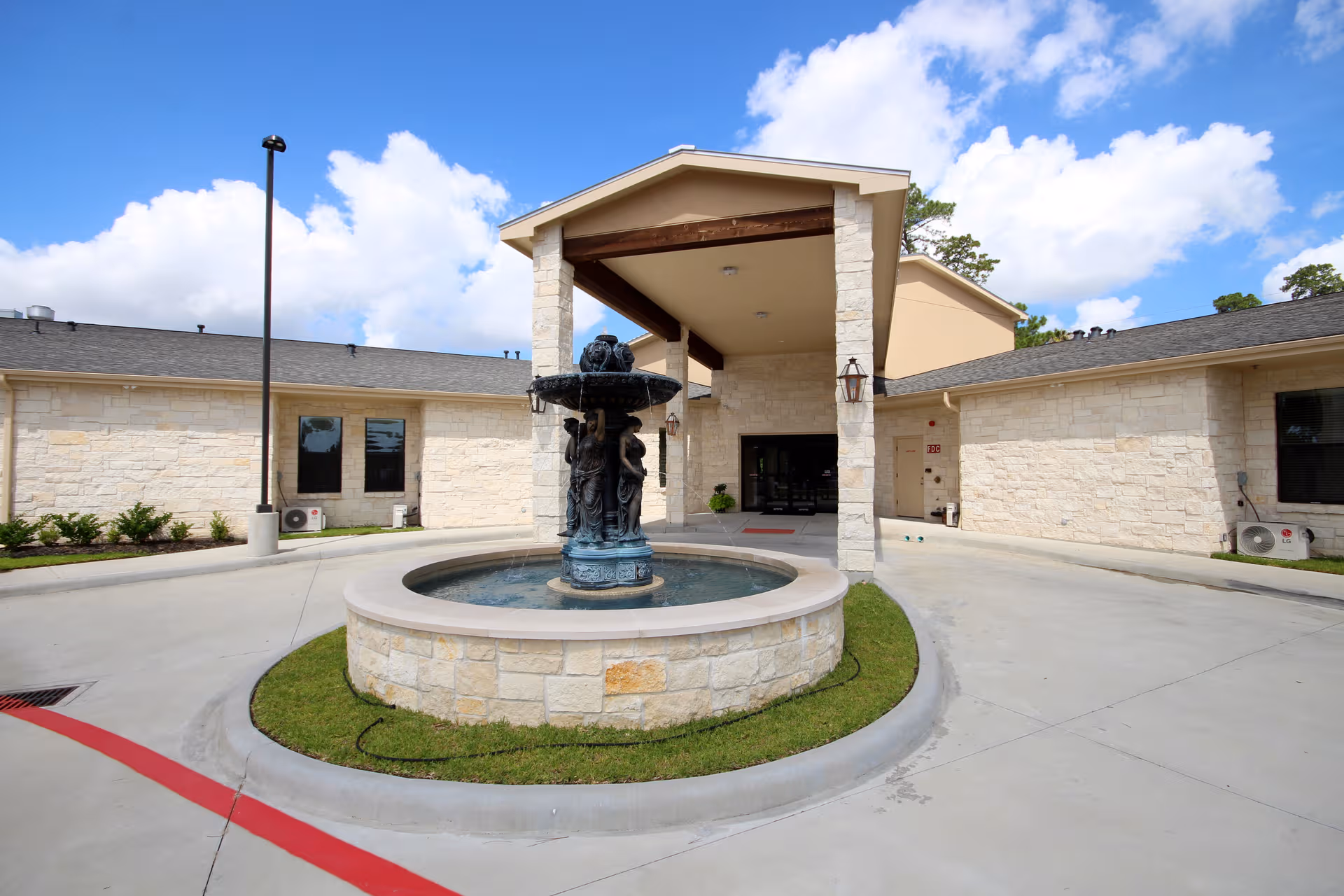 Exterior view of senior living facility entrance with circular fountain