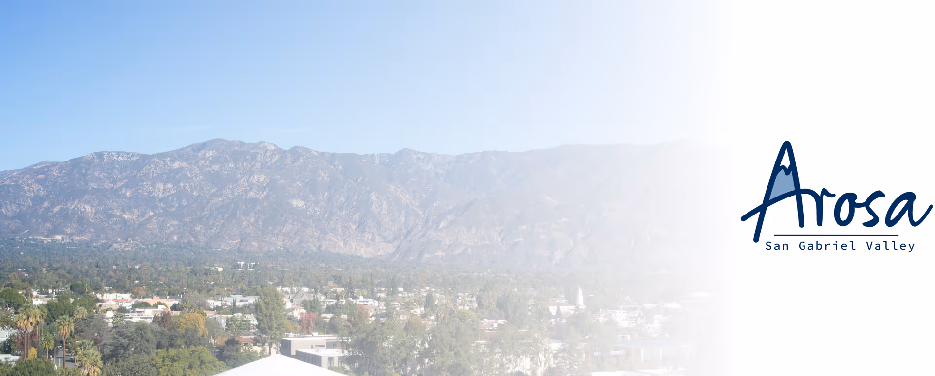 Scenic valley mountains overlook a town, with Arosa San Gabriel Valley logo on the right.