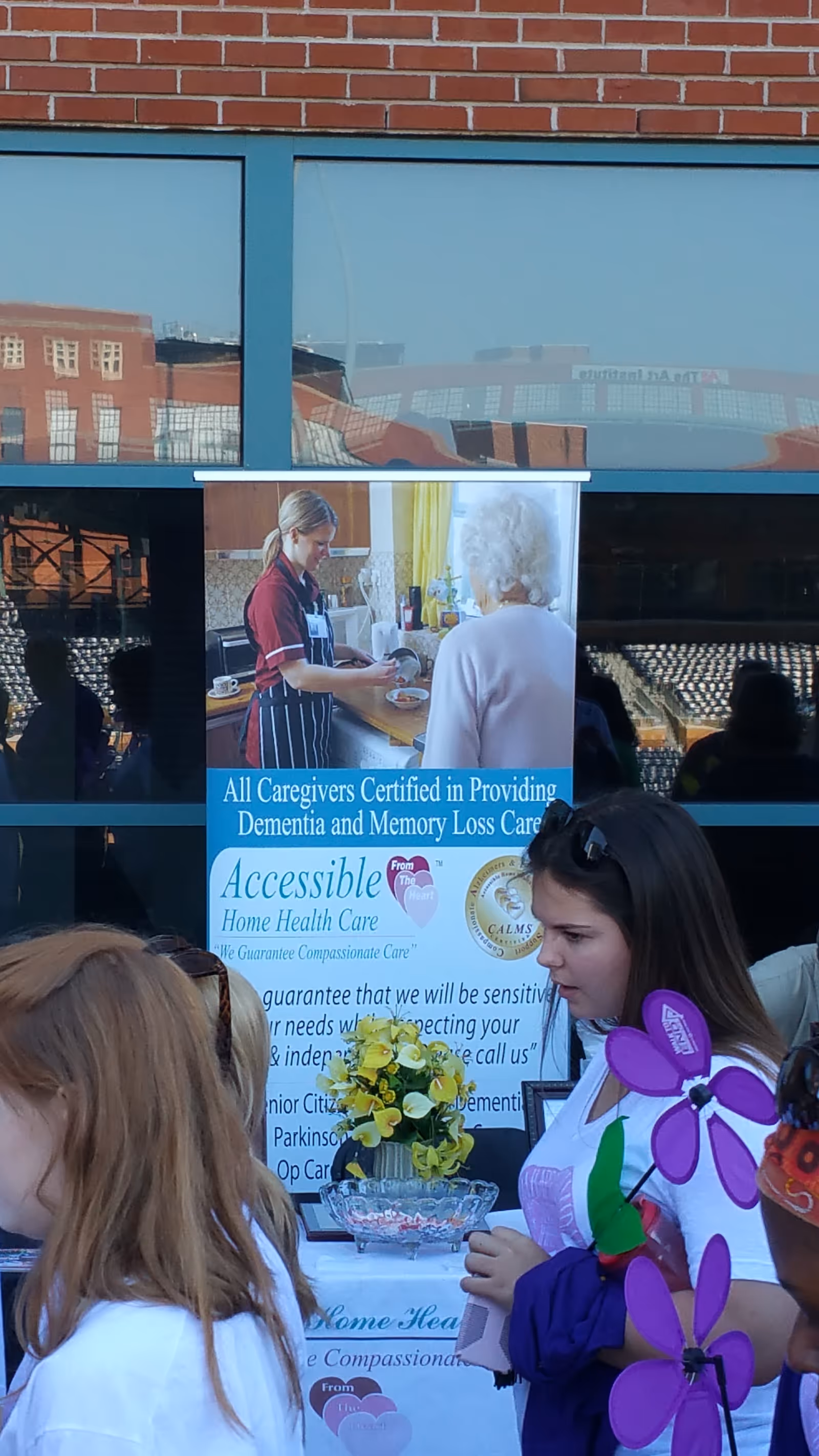 Poster for Accessible Home Care of Mid Carolina advertising dementia care on building front; people nearby.