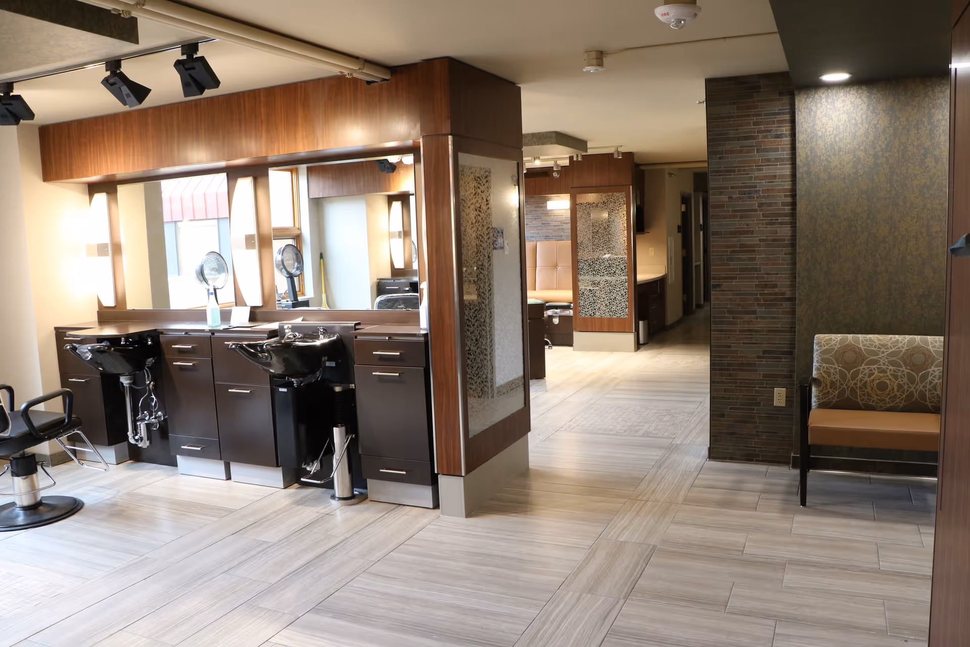 Interior hair salon area with sinks, mirrors, and dark wood cabinetry.