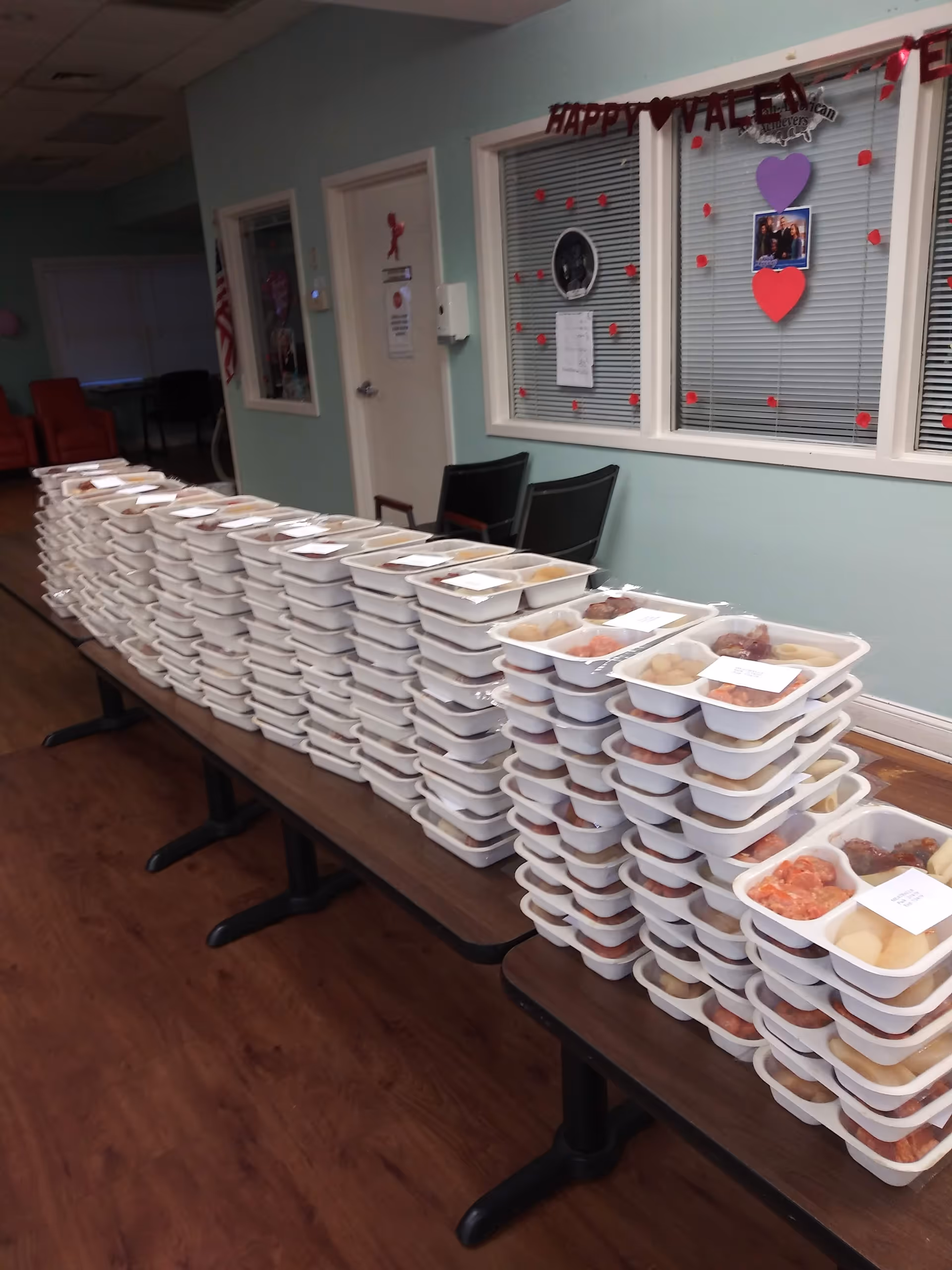 Long table stacked with meal trays in a bright hallway of the facility.