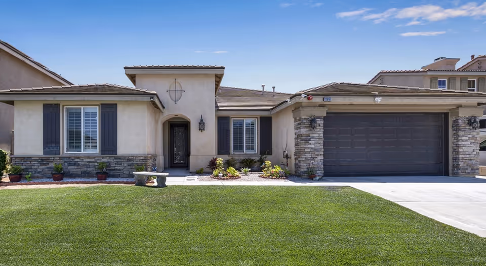 Front exterior view of a single-story home with a manicured lawn and two-car garage.
